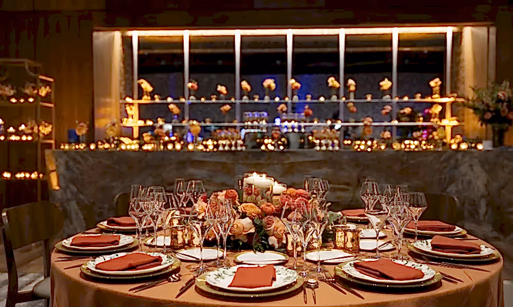 Table set up featuring orange and pink flowers in the Canyon Ballroom for wedding reception.